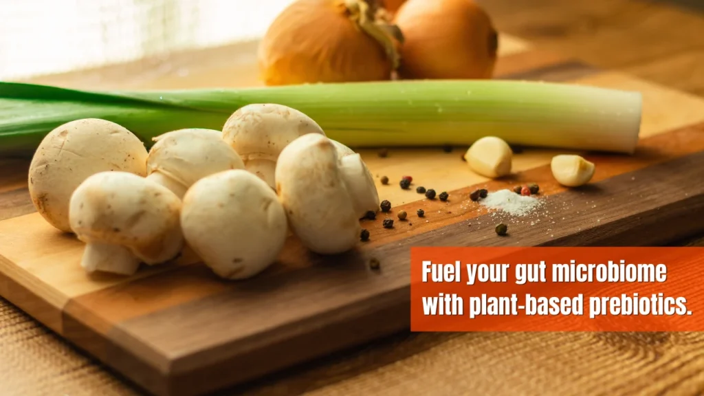 Mushrooms, onions, garlic, and leeks displayed as plant-based prebiotic foods that support gut health.